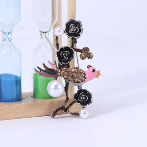 Detailed view of vintage bird brooch with black roses, pearls, and crystals on a wooden prop