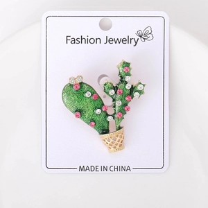 Close-up of cactus plant brooch with green enamel and sparkling rhinestones on jewelry card