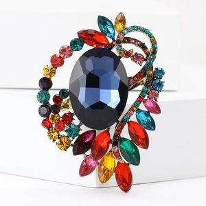 Macro detail of a vintage gold alloy brooch with deep blue stone and multi-color rhinestones