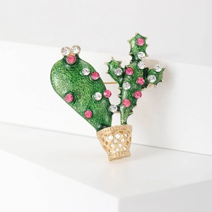 Macro detail of a cactus brooch featuring green enamel leaves and sparkling rhinestones