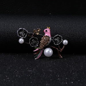 Macro shot of vintage bird brooch with rhinestones and white pearls on floral branch