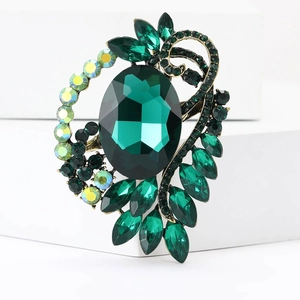 Close-up of vintage bronze brooch with emerald green crystals and AB rhinestones