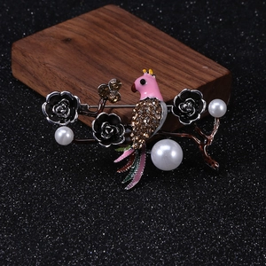Detailed close-up of a pink bird brooch with white pearls and brown rhinestones