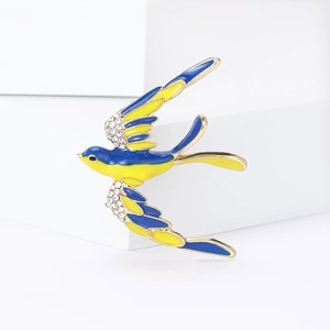 Détail d'une broche hirondelle en émail bleu et jaune avec ailes ornées de cristaux