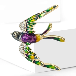 Détail macro d'une broche oiseau aux ailes en émail coloré et strass scintillants