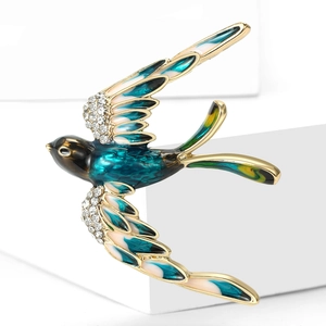 Vue détaillée de la broche hirondelle avec ailes en émail bleu et strass scintillants