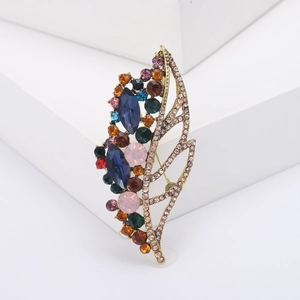 Elegant gold leaf brooch with multicolor rhinestones on a minimalist white stone background
