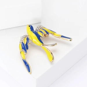 Détail d'une broche hirondelle avec émail bleu et jaune et strass blancs scintillants