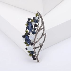 Exquisite hollow leaf brooch with multi-color rhinestones on a white geometric stand