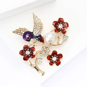 Detalle de broche de colibrí esmaltado con cristales brillantes y flor de perla blanca