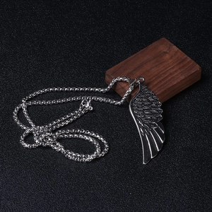 Détail d'un pendentif aile argenté sur une chaîne à mailles carrées robuste
