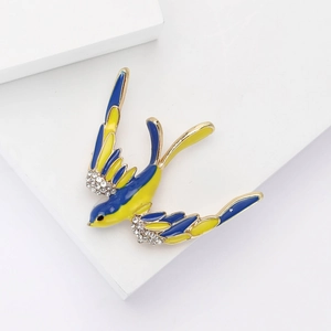 Détail de la broche hirondelle en émail aux ailes bleu et jaune ornées de cristaux