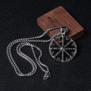 Gros plan détaillé d'un pendentif croix roue solaire rétro sur bloc de bois de noyer