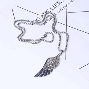 Gros plan d'un pendentif aile plume en argent avec gravure détaillée et chaîne métal