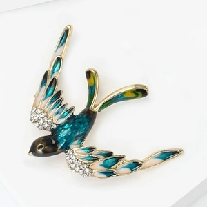 Vue macro de la broche hirondelle avec émail bleu et strass blancs finement incrustés