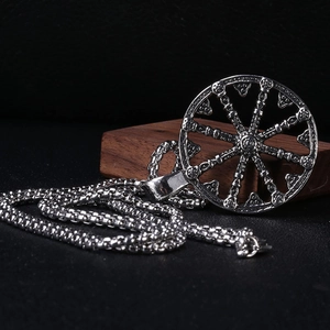 Vue détaillée du pendentif roue du dharma en argent vieilli avec relief sur chaîne à maillons carrés