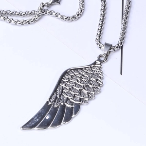 Gros plan d'un pendentif plume en acier titane argenté avec texture fine et chaîne maille