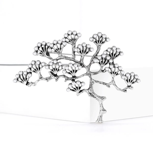 Broche branche de pin argentée vintage avec perles sur un fond blanc minimaliste élégant