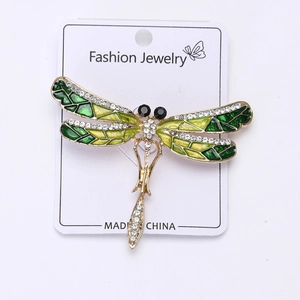 Vue détaillée de la broche libellule avec ailes en émail vert et strass étincelants