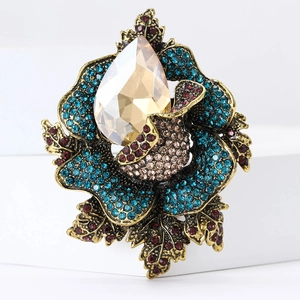 Macro detail of vintage floral brooch featuring turquoise rhinestones and amber centerpiece