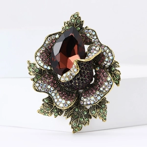 Close-up of vintage flower brooch with deep red gemstone and multi-colored crystals
