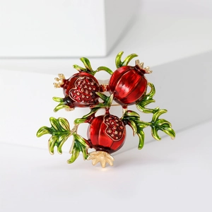 Elegant red enamel pomegranate brooch with green leaves on minimalist white steps