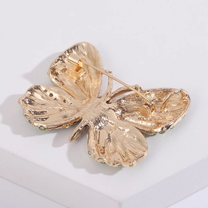 Detailansicht der Rückseite der goldenen Schmetterlingsbrosche mit Nadelverschluss und Steinen