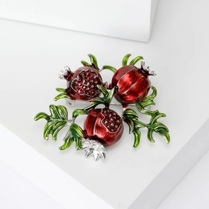 Creative red enamel pomegranate brooch with green leaves and silver metal branch detail