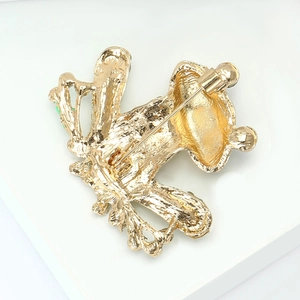 Close-up of the gold-plated alloy back and secure pin buckle of the sitting frog brooch