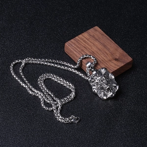 Gros plan du pendentif tête de tigre punk vintage sur chaîne sur texture cuir noir