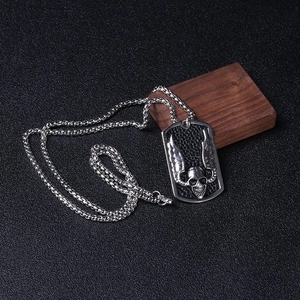 Detail of gothic silver dog tag pendant with skull and wings on black leather background