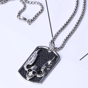 Macro detail of gothic stainless steel skull and wing pendant with black textured background