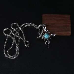 Detail of cross flame pendant with turquoise stone inlay on black leather texture