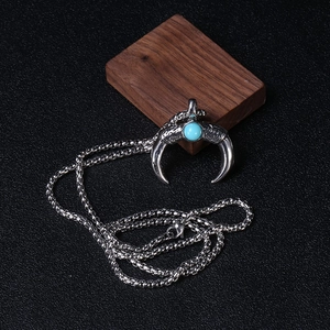 Macro detail of crescent horn pendant with blue stone and intricate dragon scales