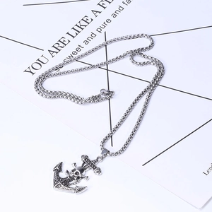 Detailed view of vintage silver anchor pendant with skull motif on a display card