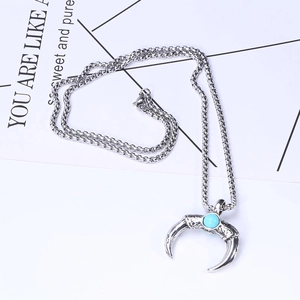 Detailed view of silver crescent moon pendant with turquoise stone and tribal carvings