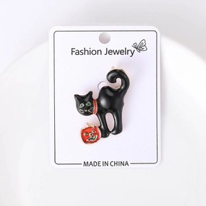 Detail of Halloween black cat brooch with red pumpkin on white display card