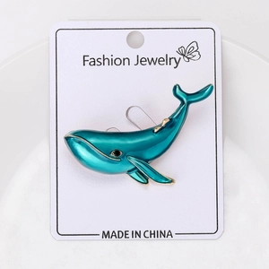 Detail view of blue whale enamel brooch with gold accents on a white jewelry display card