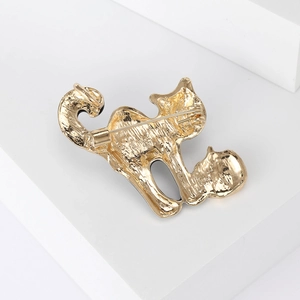 Golden cat enamel brooch with safety pin closure shown on a white geometric stage