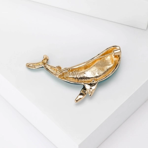 Golden dolphin alloy brooch showing detailed back pin clasp on white geometric blocks