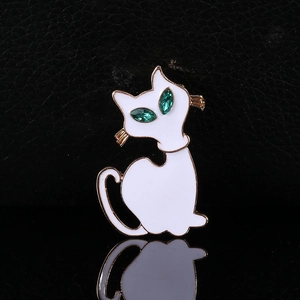 Schattige witte emaille kattenbroche met gouden randen en fonkelende groene edelstenen