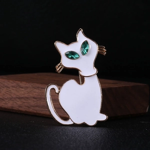 Macro-detail van witte emaille kattenbroche met levendige groene edelsteen ogen