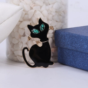 Detail van de zwarte emaille kattenbroche met groene edelstenen ogen op goud