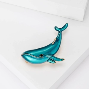 Elegant green enamel dolphin brooch with gold metal trim on white geometric background