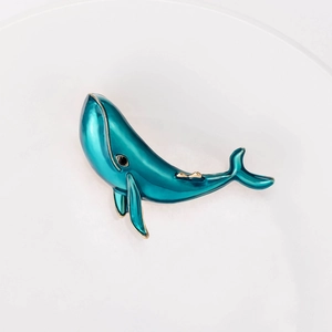 Elegant whale shaped blue enamel brooch with gold trim and minimalist dolphin design
