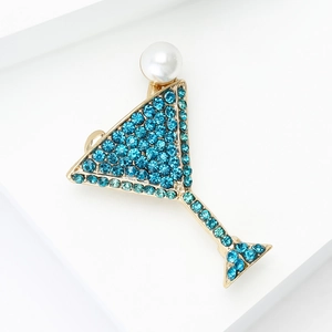 Détail de la broche verre à cocktail dorée avec strass bleus et perle blanche