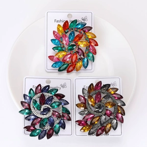 Detailed macro view of crystal spiral brooches in vibrant color palettes on white display card
