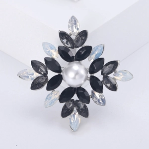 Close-up of snowflake brooch featuring central pearl and marquise rhinestones on base
