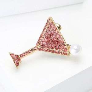 Vue macro d'une broche verre à martini en strass roses et perle sur métal doré fini