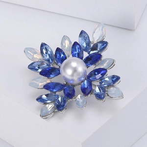 Elegant snowflake brooch with blue crystals and a large white pearl on a silver base